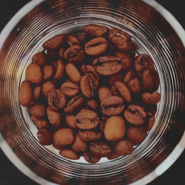 Close-up of roasted coffee beans inside a metallic container.