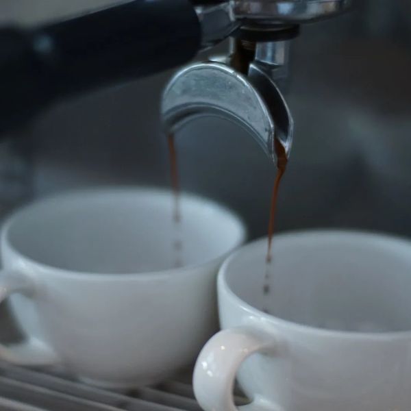 Espresso coffee being brewed into two white cups.