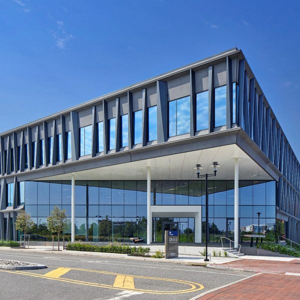 Modern office building with reflective glass windows under a clear blue sky.