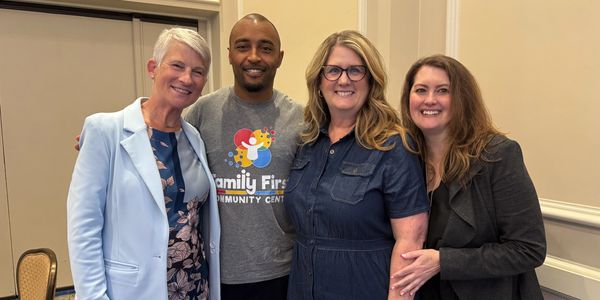 Four adults smiling together indoors, showing camaraderie and warmth.