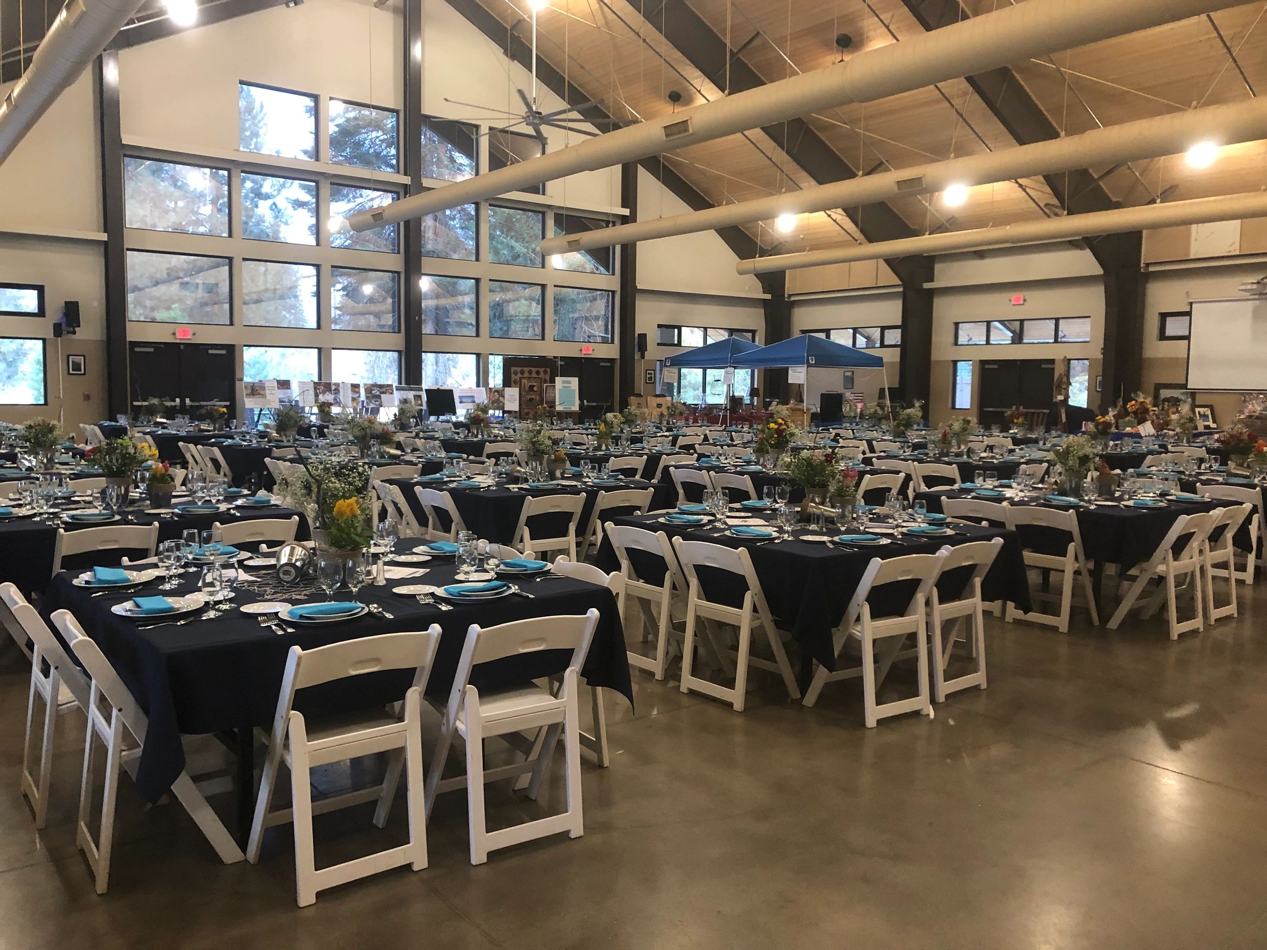 Large banquet hall with decorated tables and white chairs.
