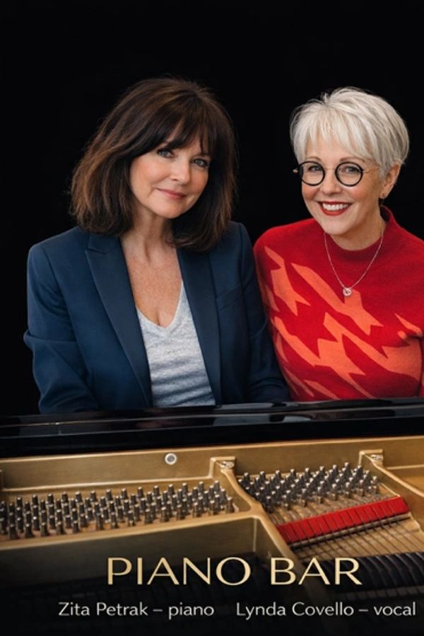 Two women, Zita Petrak and Lynda Covello, pose behind a piano for a Piano Bar event.