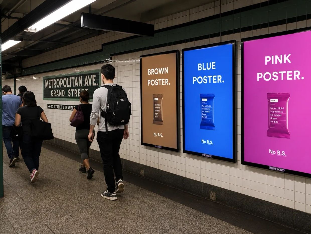 People walk past colorful posters advertising healthy snacks at a subway station.