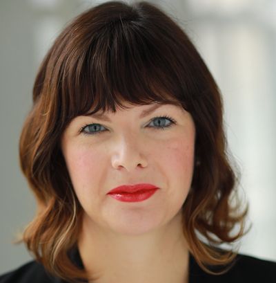 Woman with brown hair and red lipstick smiling gently.