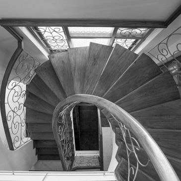 Elegant curved wooden staircase with decorative iron railings.