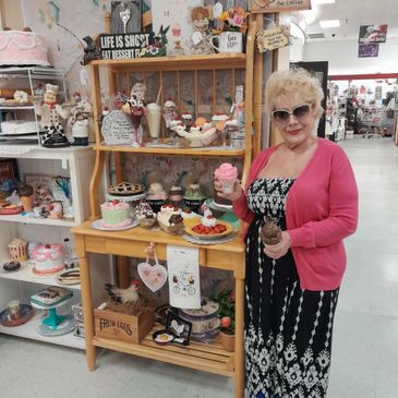 Elderly woman holding ice cream cones in a store with cakes and decorations.
