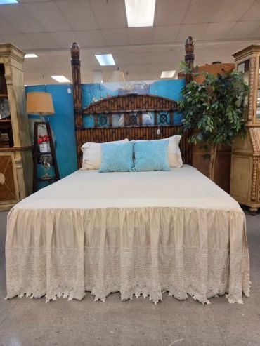 Bamboo style bed with lace bed skirt and blue pillows.