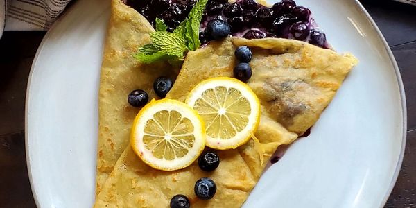 Blueberry crepes with lemon slices and mint garnish.