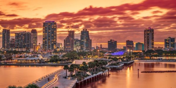 City skyline at sunset with vibrant orange sky and waterfront view.