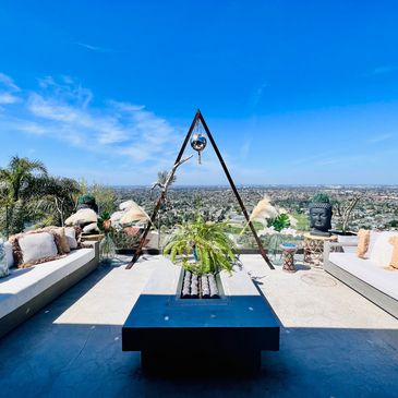 Outdoor seating area with panoramic city view and triangular metal sculpture.