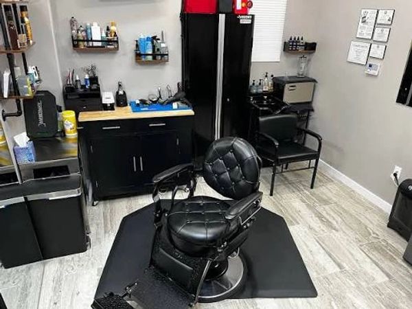 Modern barbershop interior with a black barber chair and organized shelves.