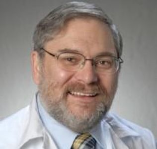 Smiling man in glasses with a white coat and tie.