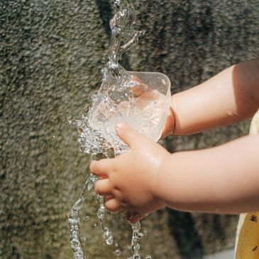 Child's hands pouring water from a cup.