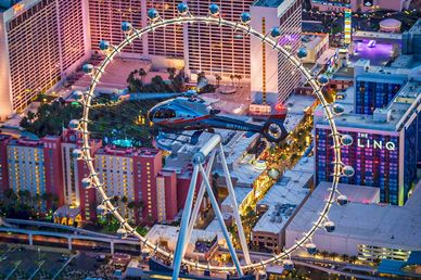 Helicopter flying near a large Ferris wheel at night.