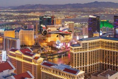 Helicopter flying over Las Vegas cityscape at dusk.