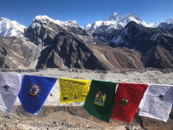 Colorful prayer flags with snowy Himalayan mountains in the background.
