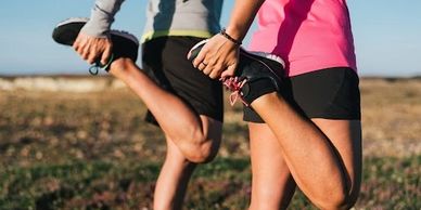 Two people stretching their legs outdoors before running.