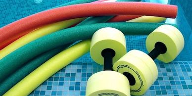 Colorful pool noodles and yellow dumbbells on a tiled surface.