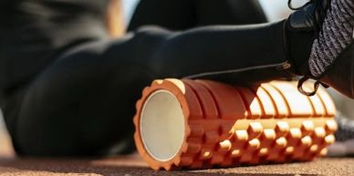 Person using an orange foam roller for muscle relief.