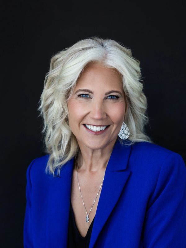 Smiling woman with blonde hair in blue blazer.