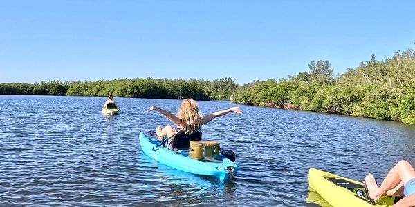 People kayaking on a sunny lake with clear blue skies.