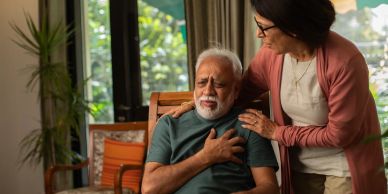 Woman supports man experiencing chest pain.