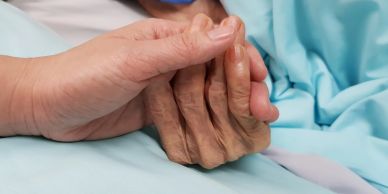 Two hands clasped together, showing care and support.