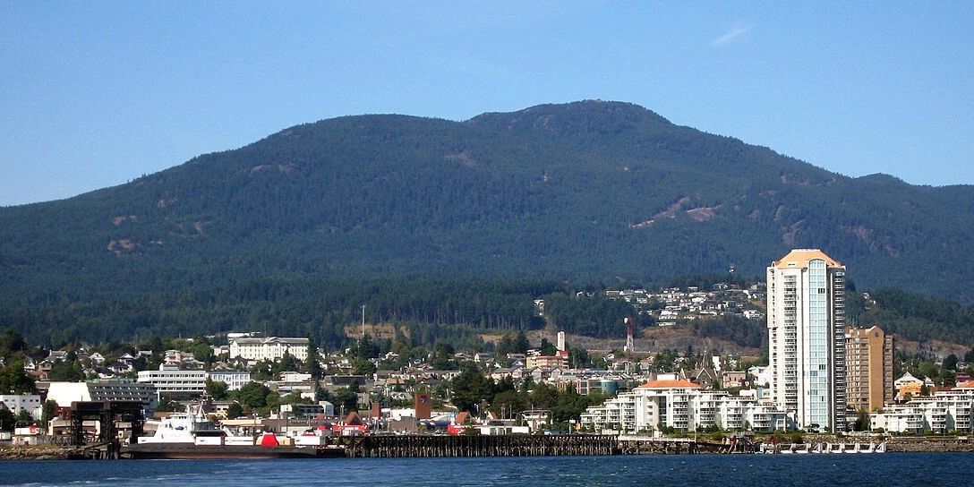 Coastal cityscape with mountains in the background under a clear sky.