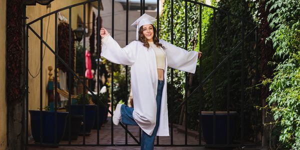 High school graduate in cap and gown posing outdoors in Albuquerque
