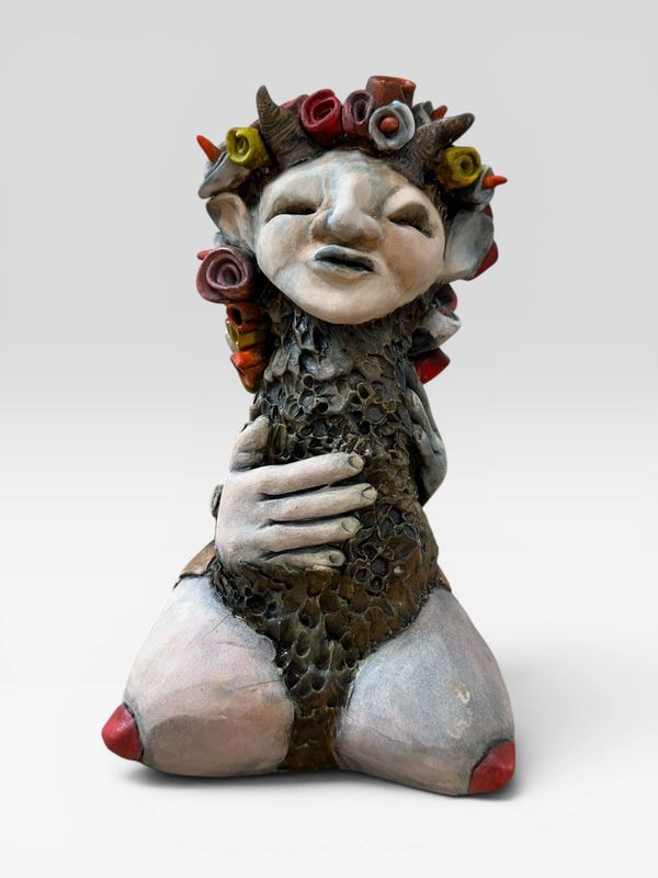 A whimsical ceramic sculpture of a horned figure with floral headgear and textured body.