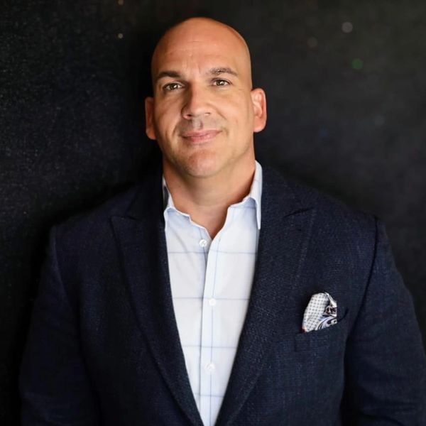 Smiling bald man in a suit jacket with a pocket square.