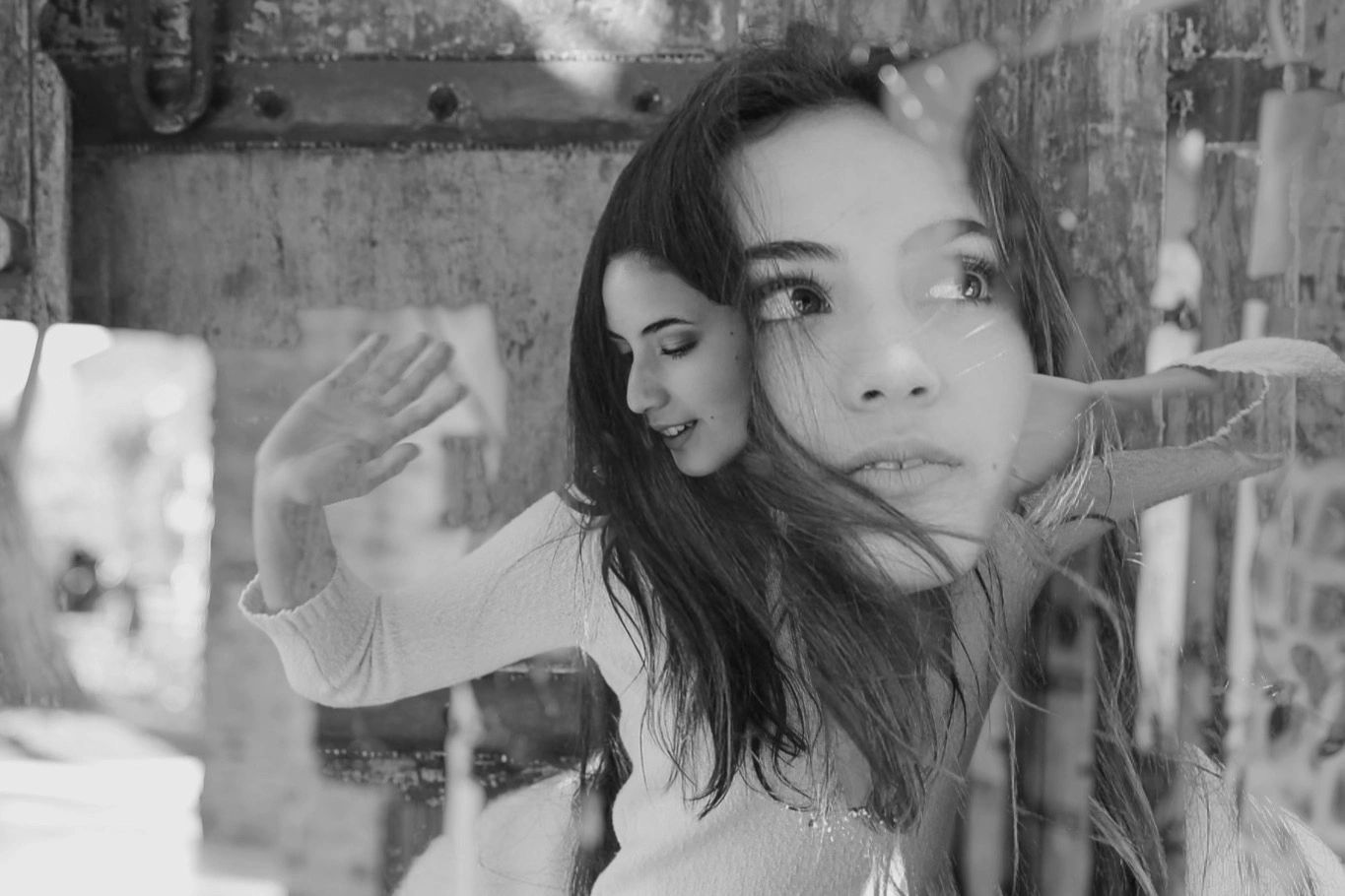 Double exposure portrait of a contemplative woman with flowing hair in black and white.