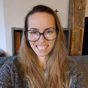 Image of Natasha wearing glasses, long hair let down, and smiling