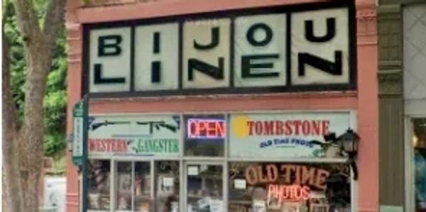 Storefront with a sign spelling 'BLIND JOEZ' and neon 'OPEN' sign.