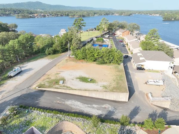 Aerial view of a lakeside community with empty plots and houses near water.