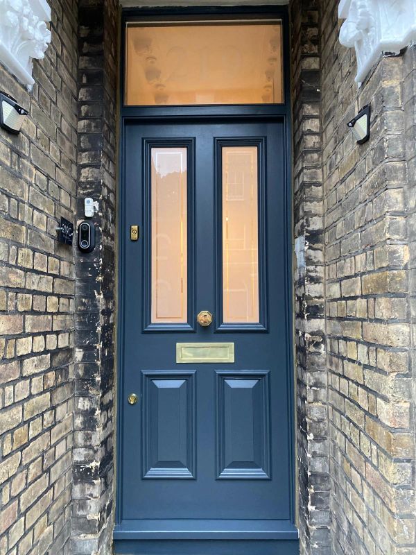 Elegant blue front door with brass fixtures set in a brick facade.