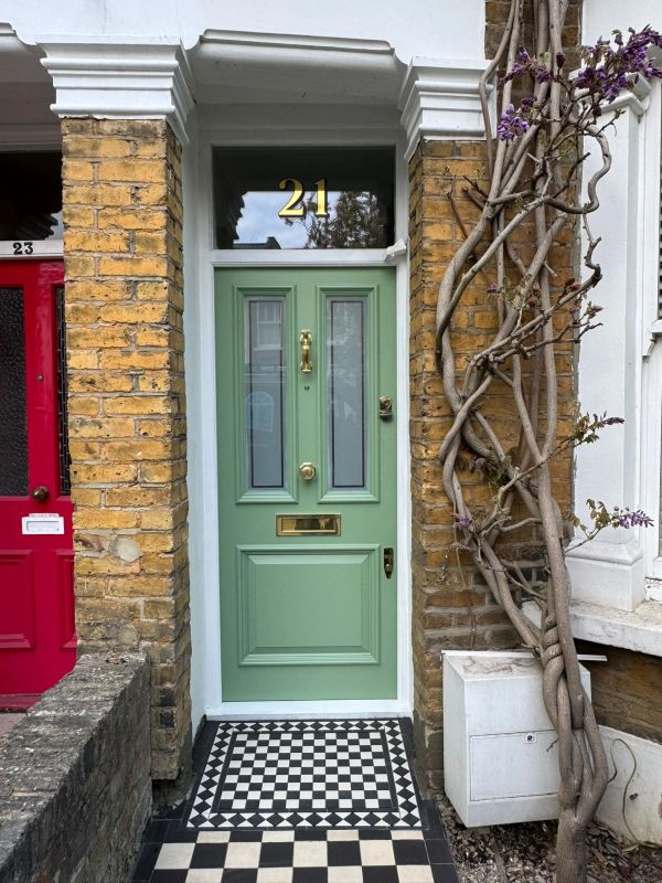 A pastel green door numbered 21 with a checkerboard tiled doorstep.