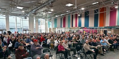 Large audience seated in a colorful indoor venue for an event.