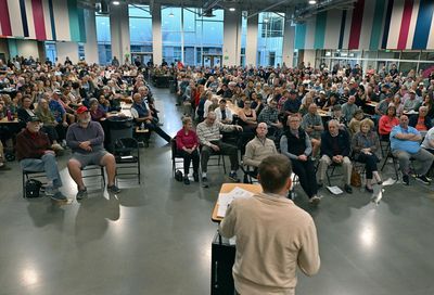 A speaker addressing a large audience in a modern hall.