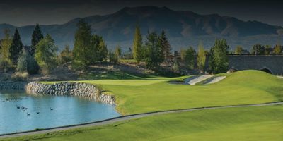 Scenic golf course with water and mountains in the background.