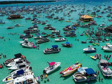 Numerous boats and people gather in clear turquoise water for a lively event.