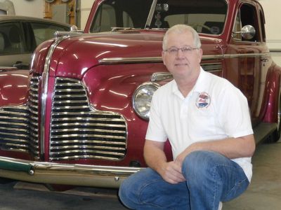 Man posing with a vintage red car.