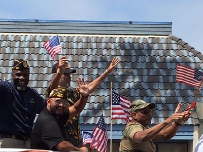 Group of VFW members waving flags during an Independence Day Parade.