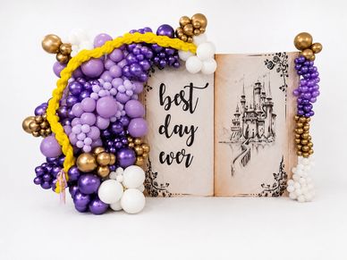 A colorful balloon arrangement around a fairy tale castle backdrop.
