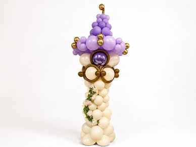 A balloon sculpture resembling a whimsical tower with purple and cream colors.