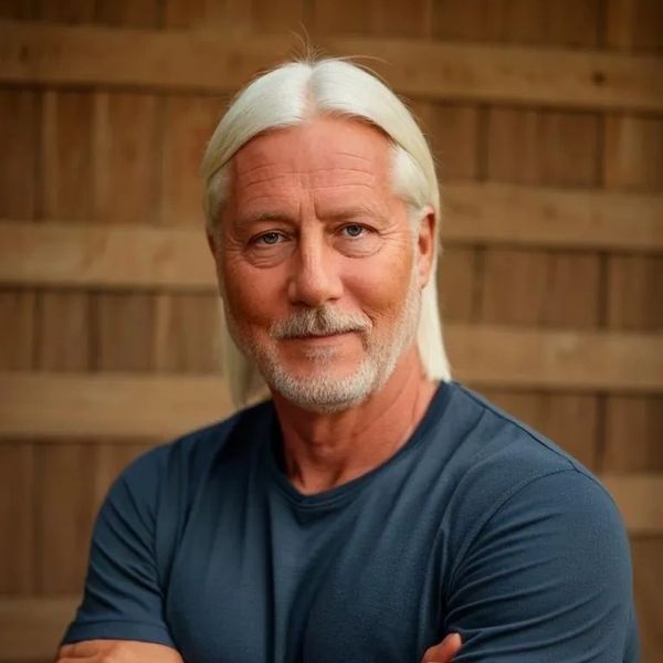 Confident older man with white hair and beard wearing a blue shirt.