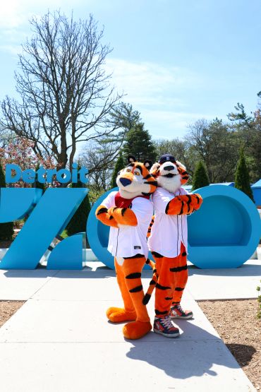 Two tiger mascots pose at Detroit Zoo entrance.