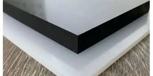 Close-up of two stacked rectangular sheets, black on top and white below, on a wooden surface.