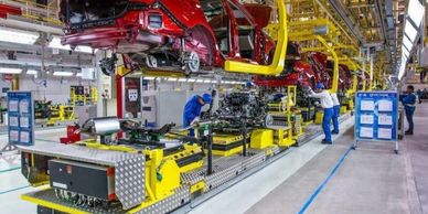 Workers assembling cars on an automated production line in a factory.