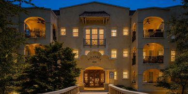 Well-lit building entrance at night with arches and balconies.